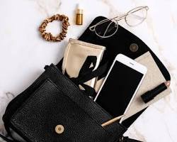 Luxury fashion accessory flatlay - Designer sunglasses, leather phone case, and crossbody bag on marble.
