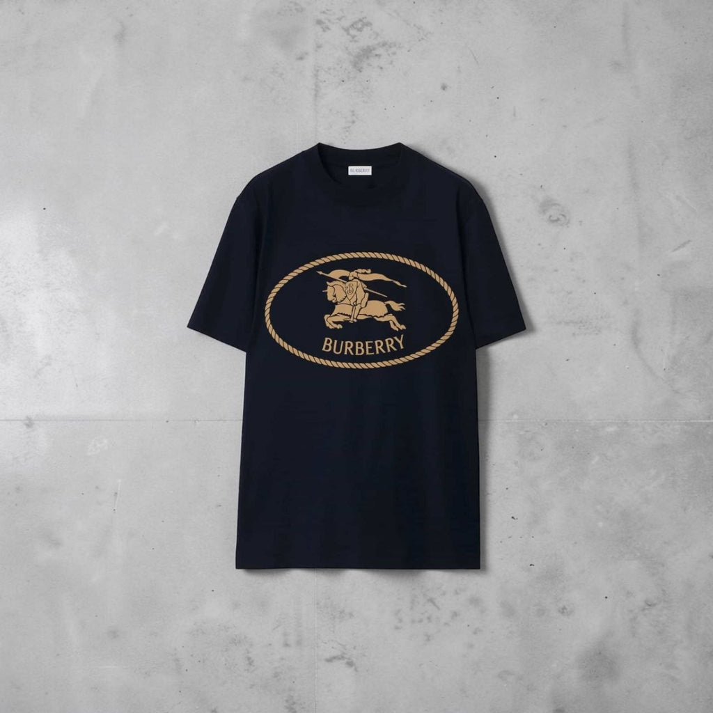 Close-up of the gold Burberry Equestrian Knight Design (EKD) logo on a navy t-shirt.