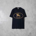 Close-up of the gold Burberry Equestrian Knight Design (EKD) logo on a navy t-shirt.