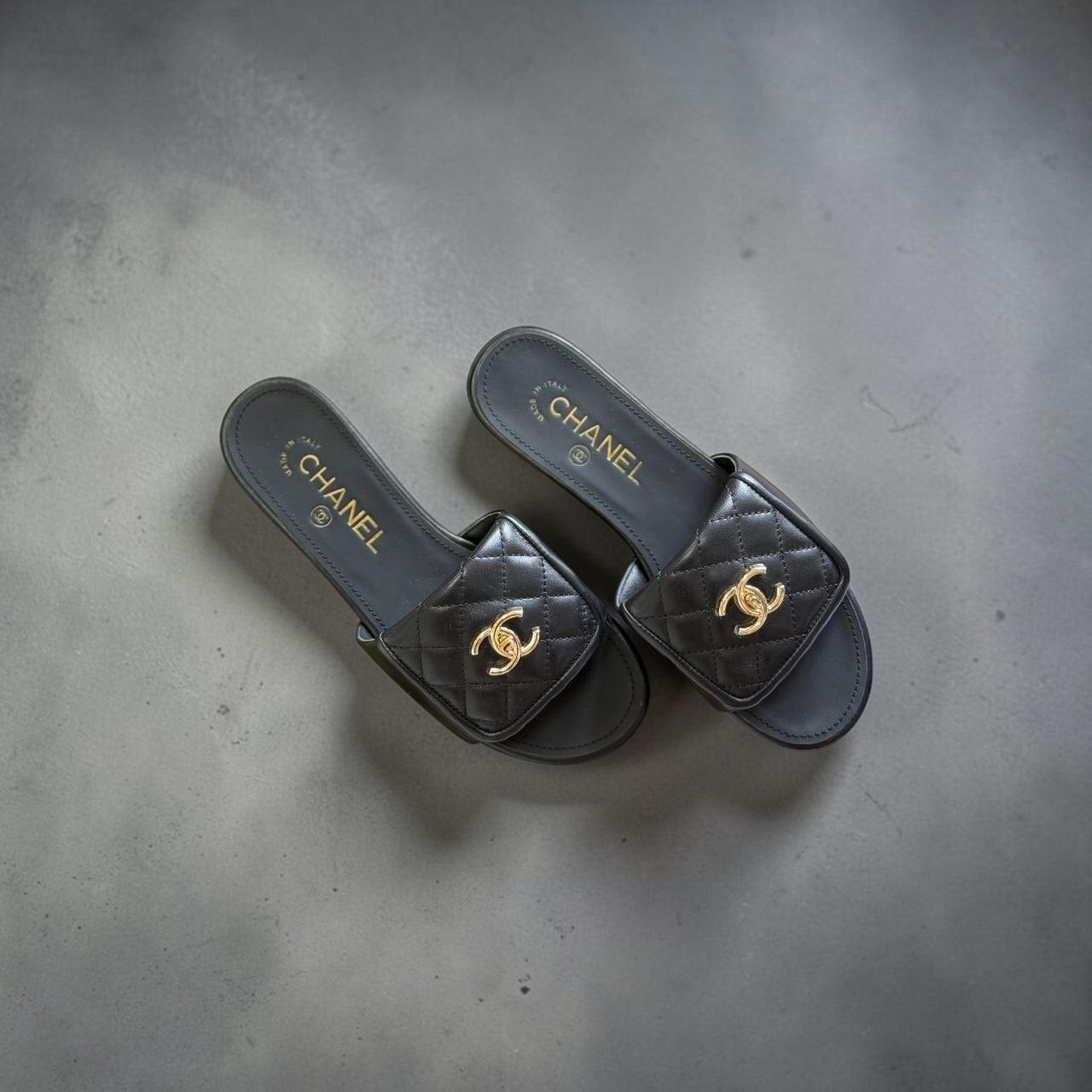 Top view of black Chanel quilted lambskin mules with gold CC logo.