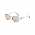 Model sitting in a cafe wearing Miu Miu MU 52YS silver oval metal sunglasses.