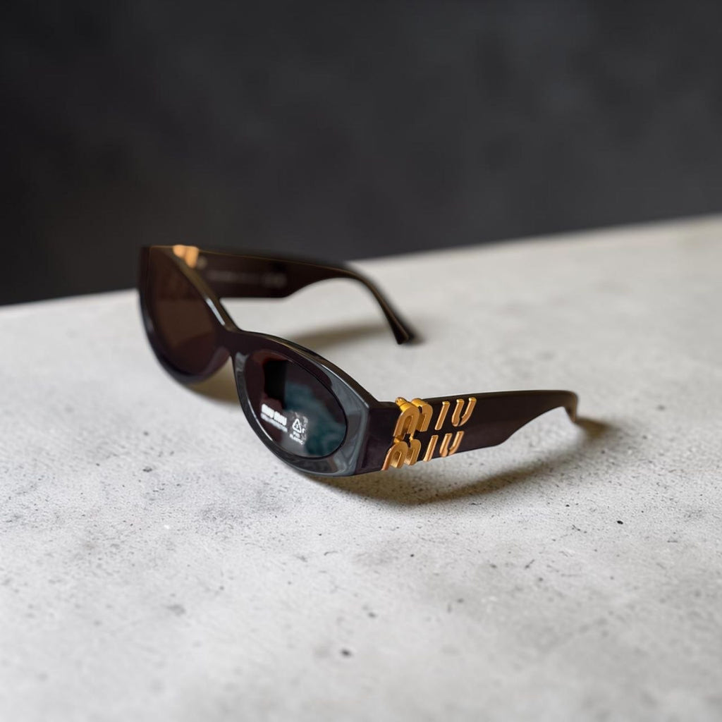 Side view of Miu Miu MU 11WS sunglasses showcasing the bold gold-tone hinge logo.