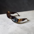 Side view of Miu Miu MU 11WS sunglasses showcasing the bold gold-tone hinge logo.