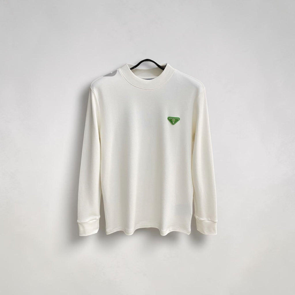 Model wearing a cream Prada crewneck sweatshirt with a green triangle logo on a European street.