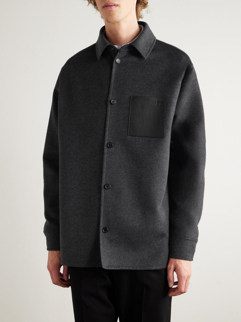 Detailed view of the LOEWE debossed Anagram on a black leather pocket against charcoal wool."