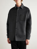 Detailed view of the LOEWE debossed Anagram on a black leather pocket against charcoal wool."